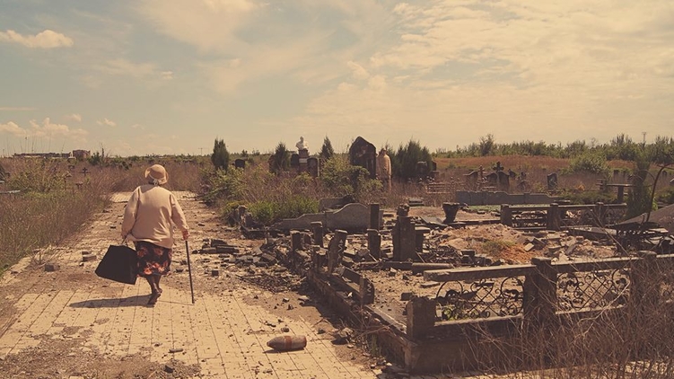 Пожилая женщина ищет могилу родственника на разрушенном Ново-Игнатьевском кладбище возле аэропорта Донецка в мае 2016 года, фото: Тоша Баешко/Facebook