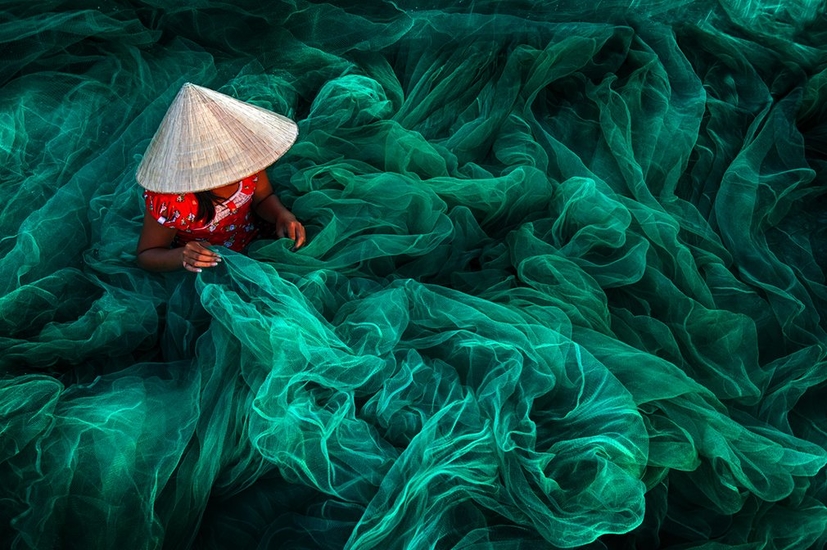 В небольшом селе рядом с городом Фанранг женщина в традиционной шляпе шьёт рыболовные сети. Производство сетей вручную – основная занятость местных жительниц, чьи мужья занимаются рыболовством

Фото: Danny Yen Sin Wong